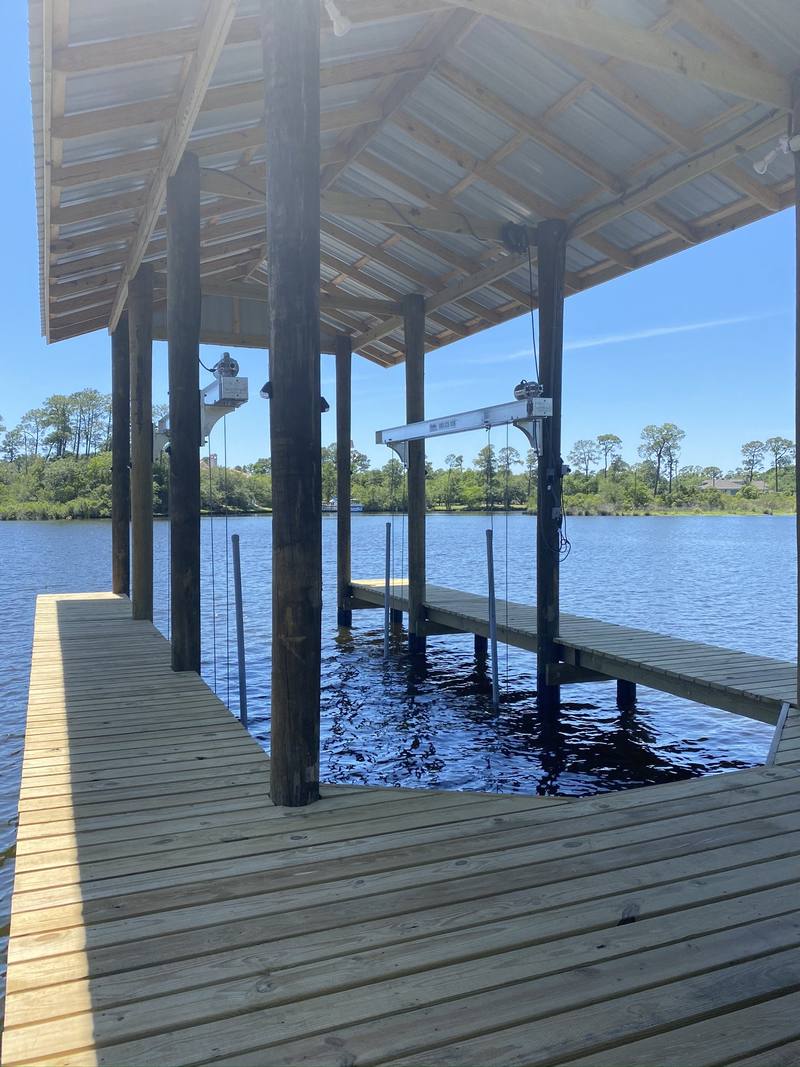 Boathouse deck with a lift between the pilings, looking out over the river