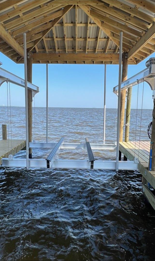 Inside a new boathouse: two boat lift cradles over open water with the bay beyond