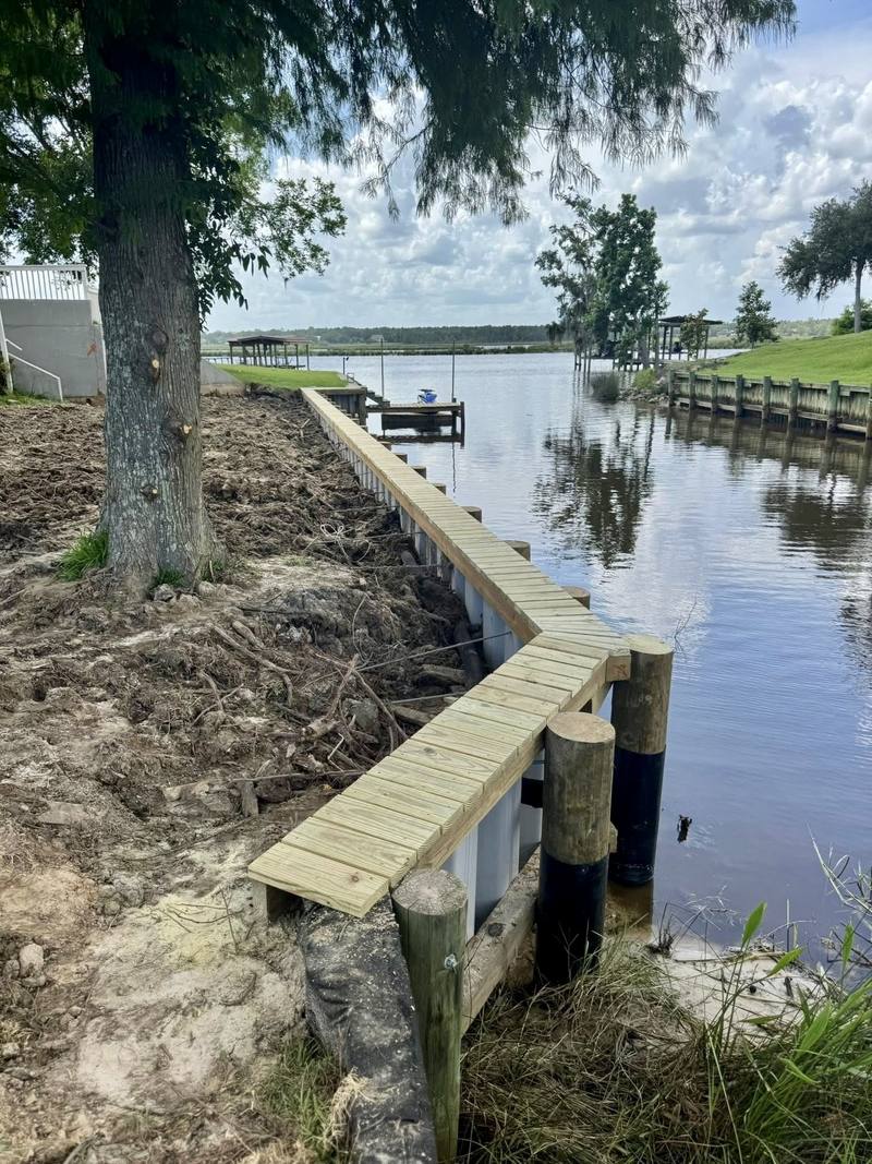Wooden bulkhead turning along the bank of a bayou lined with docks
