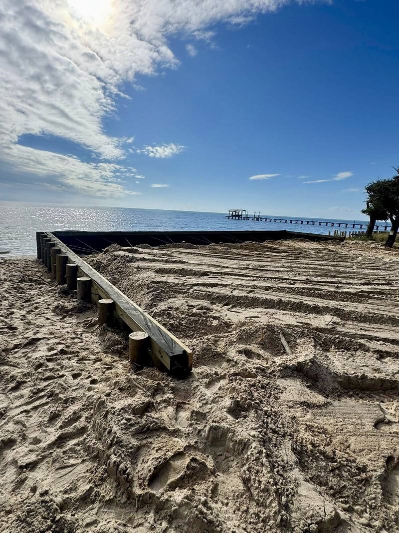 New bulkhead with sand backfill, the bay and a long pier behind it