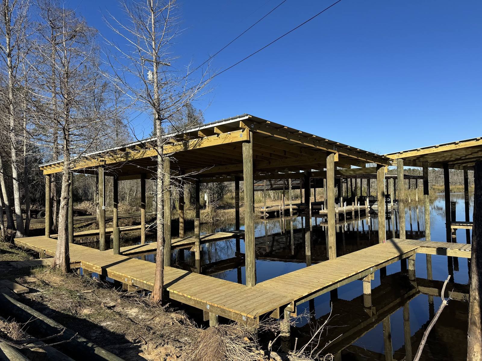 Wooden boathouse with two covered slips standing in a cypress-lined bayou