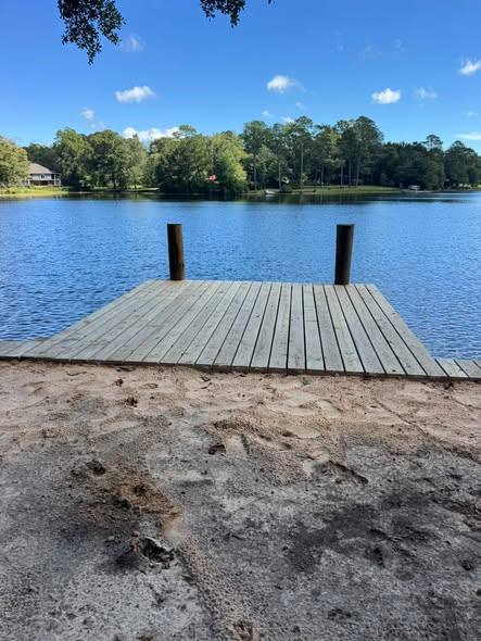 Square wooden deck with two posts at the water&rsquo;s edge on a sandy bank